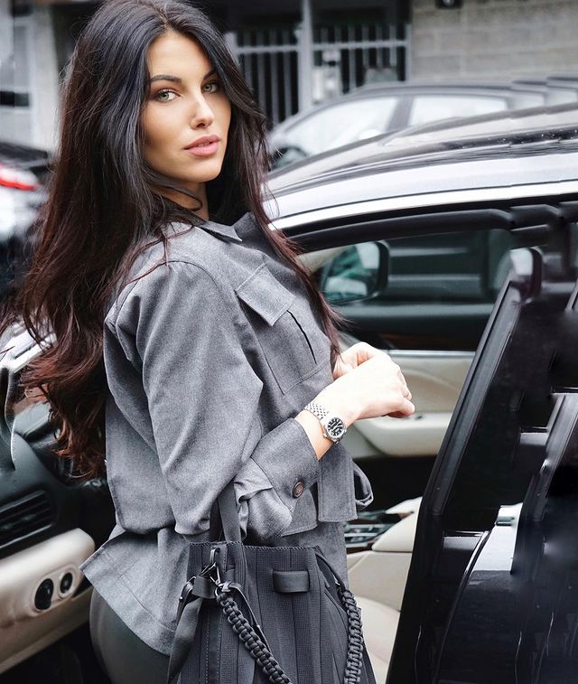 Carolina Stramare in a grey shirt and pants posing in front of her car.